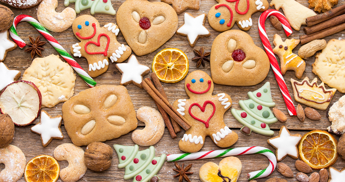 Weihnachtlicher Plätzchen-Mix aus Lebkuchen, Zimtsternen, Zuckerstangen und getrockneten Orangenscheiben auf rustikalem Holz.