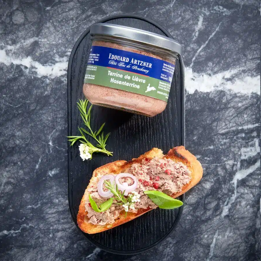 Edouard Artzner Hasenterrine im Glas mit angerichtetem Baguette und frischen Kräutern