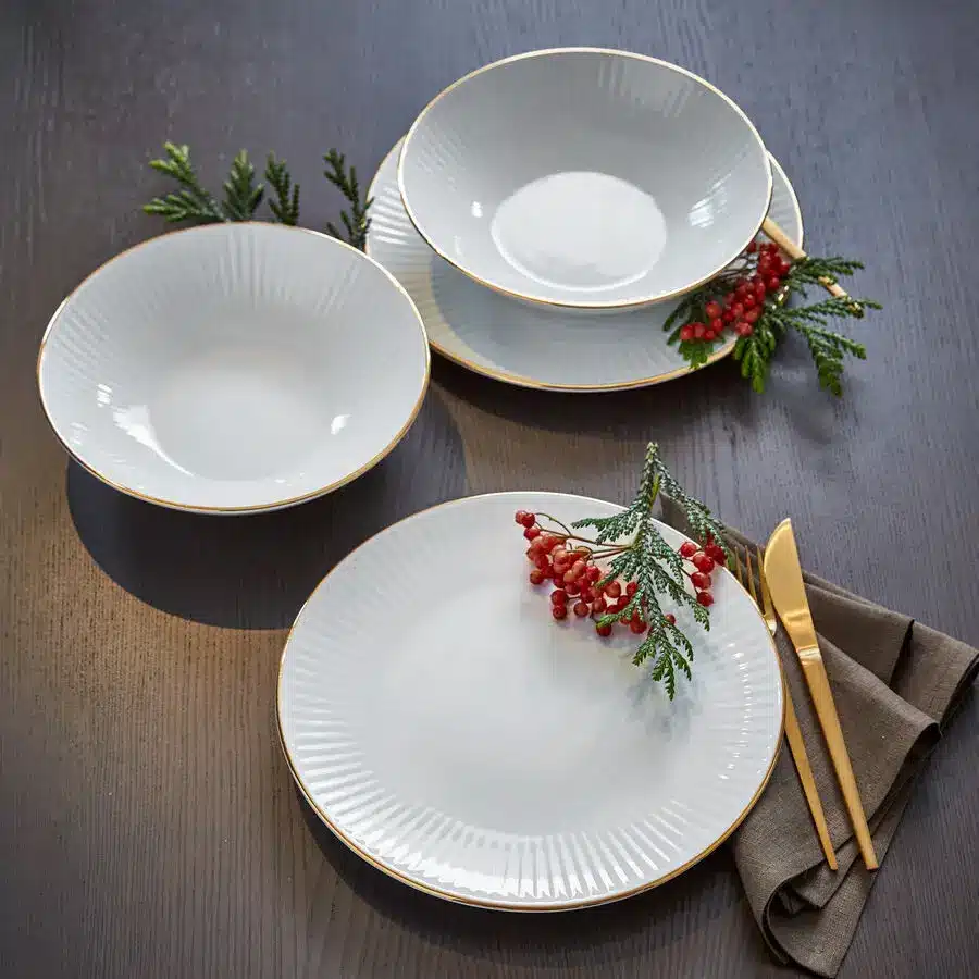 Elegantes weißes Geschirr mit Goldrand, ergänzt durch goldenes Besteck und Beeren