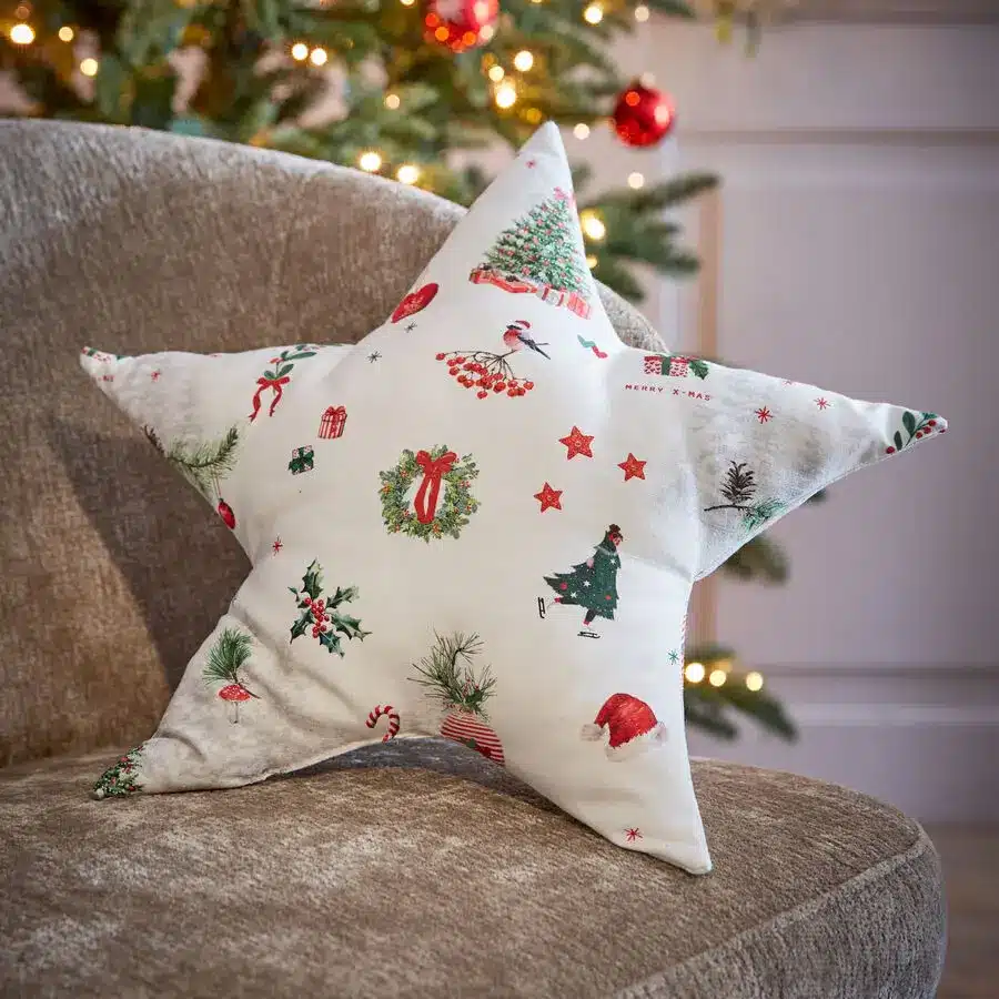 Weißes Sternkissen mit bunten Weihnachtsmotiven wie Tannenbaum, Geschenk und Schneemann