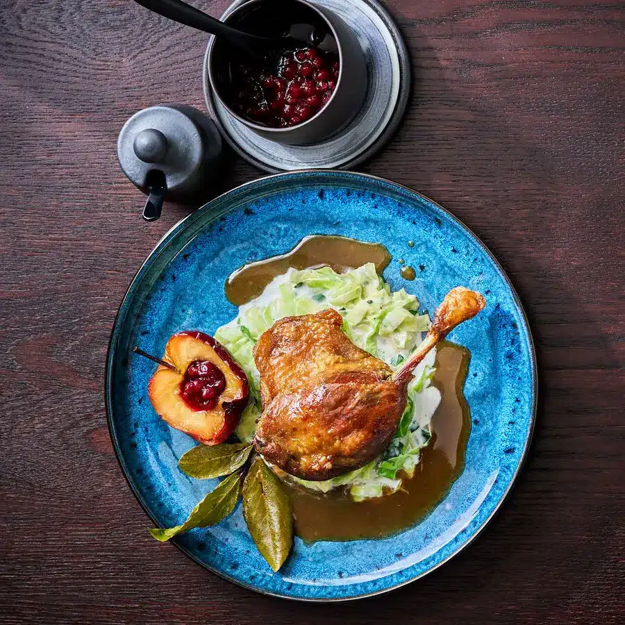 Französisches Confit de Canard, krosse Entenschenkel in feiner Sauce auf Gemüsebeilage