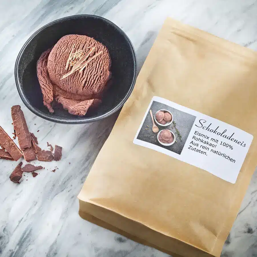 Schokoladeneis in schwarzer Schale mit Schokospänen, daneben Eismix-Tüte für natürliches Schokoladeneis.