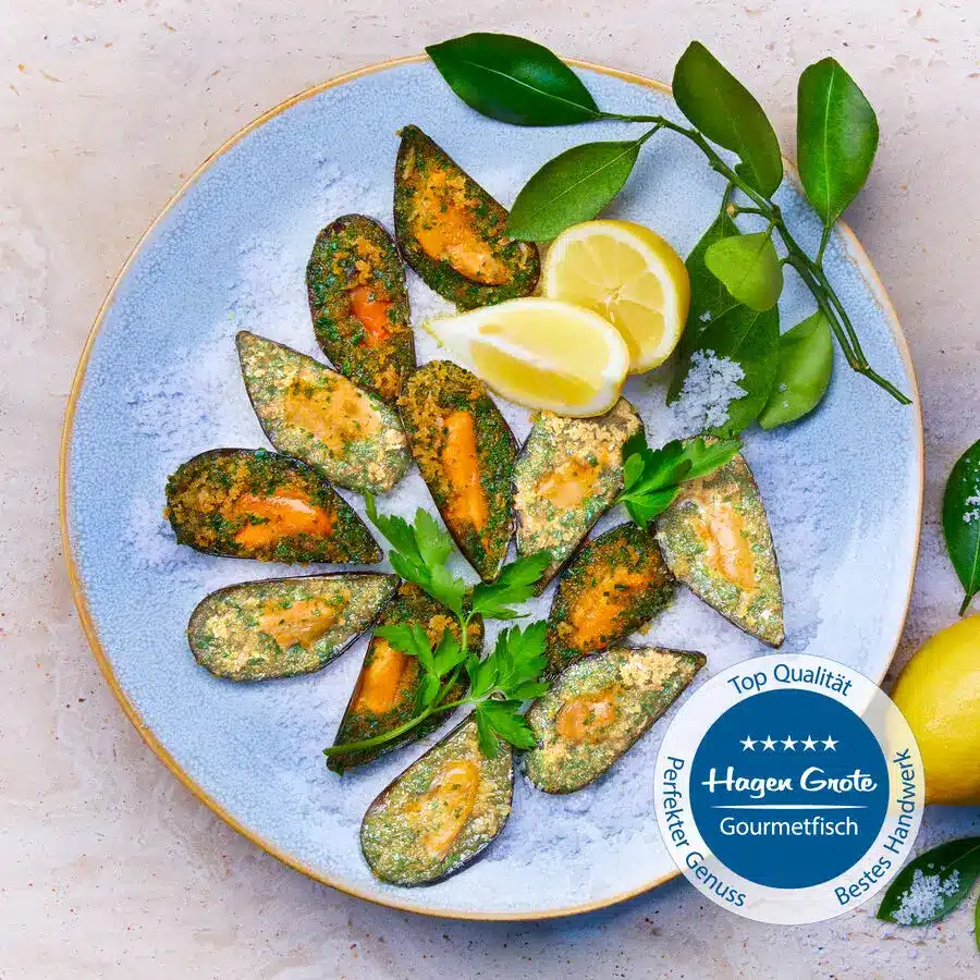 Teller mit gratinierten Miesmuscheln in Kräuterbutter, dekoriert mit Petersilie und Zitronenspalten