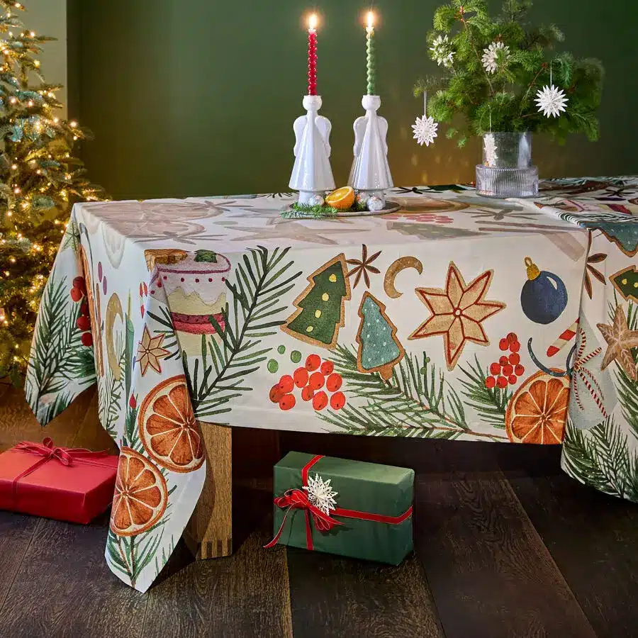 Weihnachtliche Tischdecke mit Plätzchen-, Tannen- und Orangenmotiven, festlich gedeckt