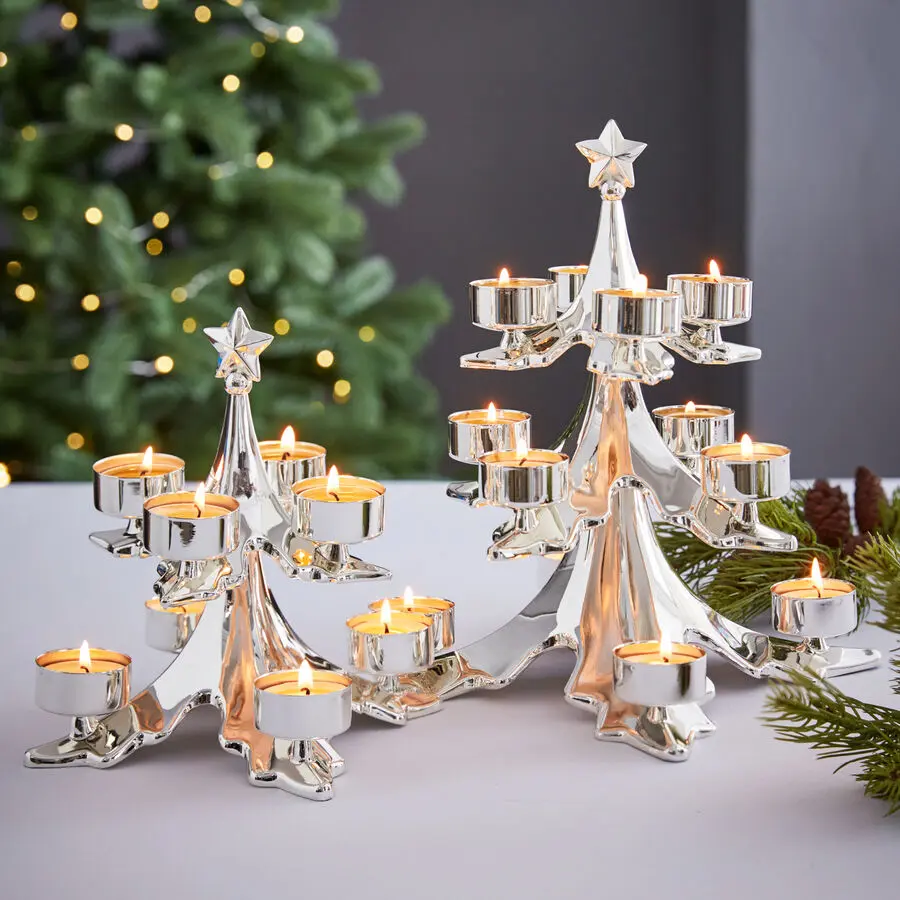 Zwei silberne Teelichthalter in Weihnachtsbaumform mit Stern, bestückt mit vielen brennenden Teelichtern als festliche Deko