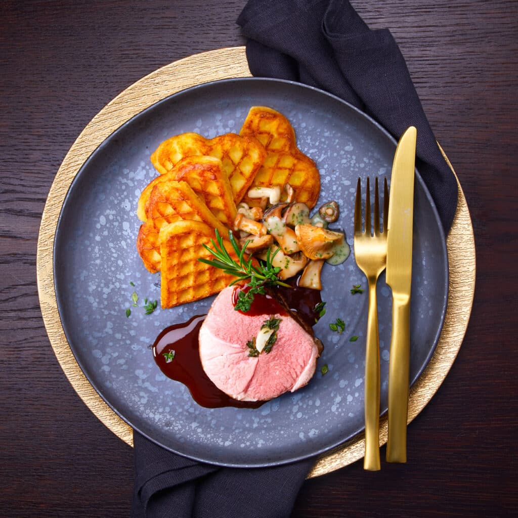 Zartes Fleisch mit Pilzen und knusprigen Kartoffelwaffeln für festliche Tafeln.