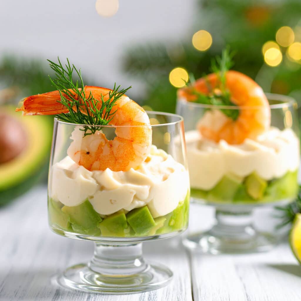Avocado-Garnelen-Cocktail im Glas mit cremiger Sauce und Dill, festlich angerichtet mit weihnachtlicher Dekoration