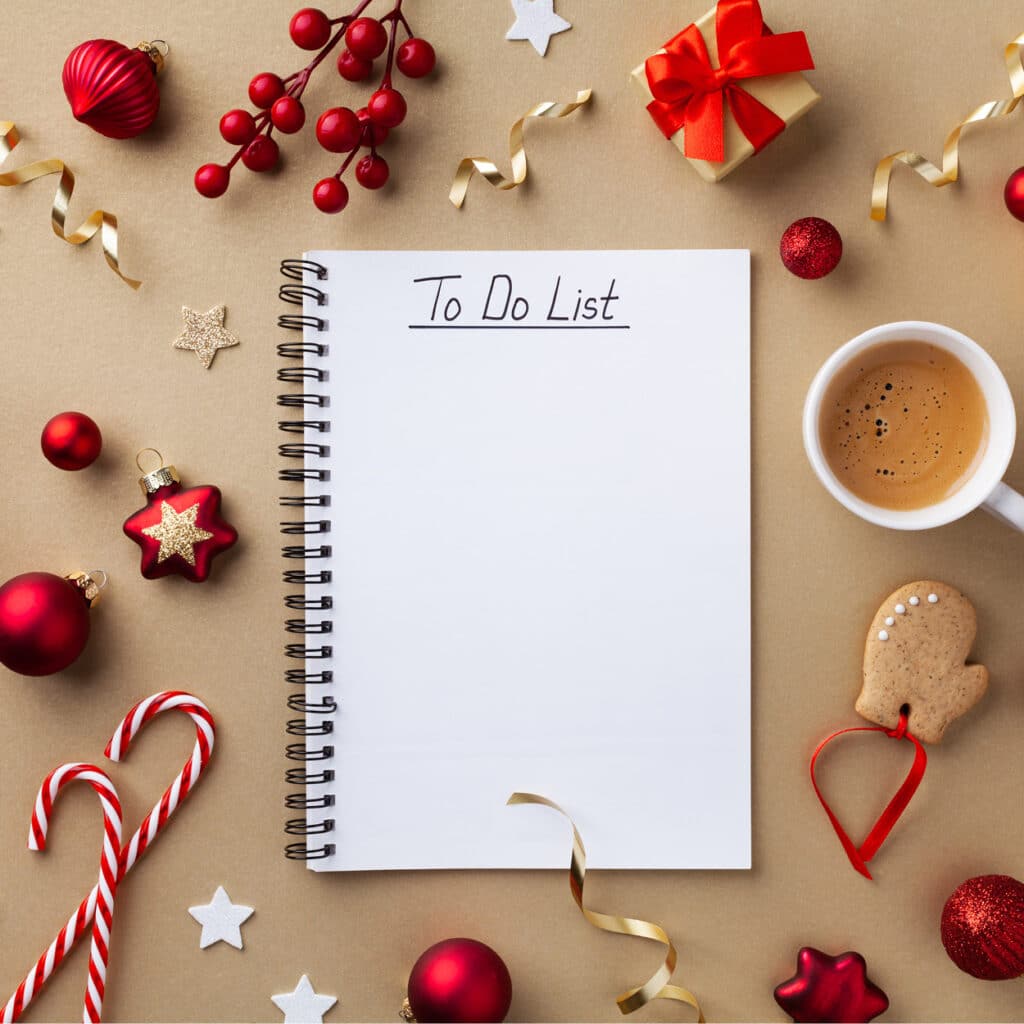 Notizbuch mit To-Do-Liste, umrahmt von Weihnachtsdeko, Kaffee, Geschenk und Lebkuchenhandschuh