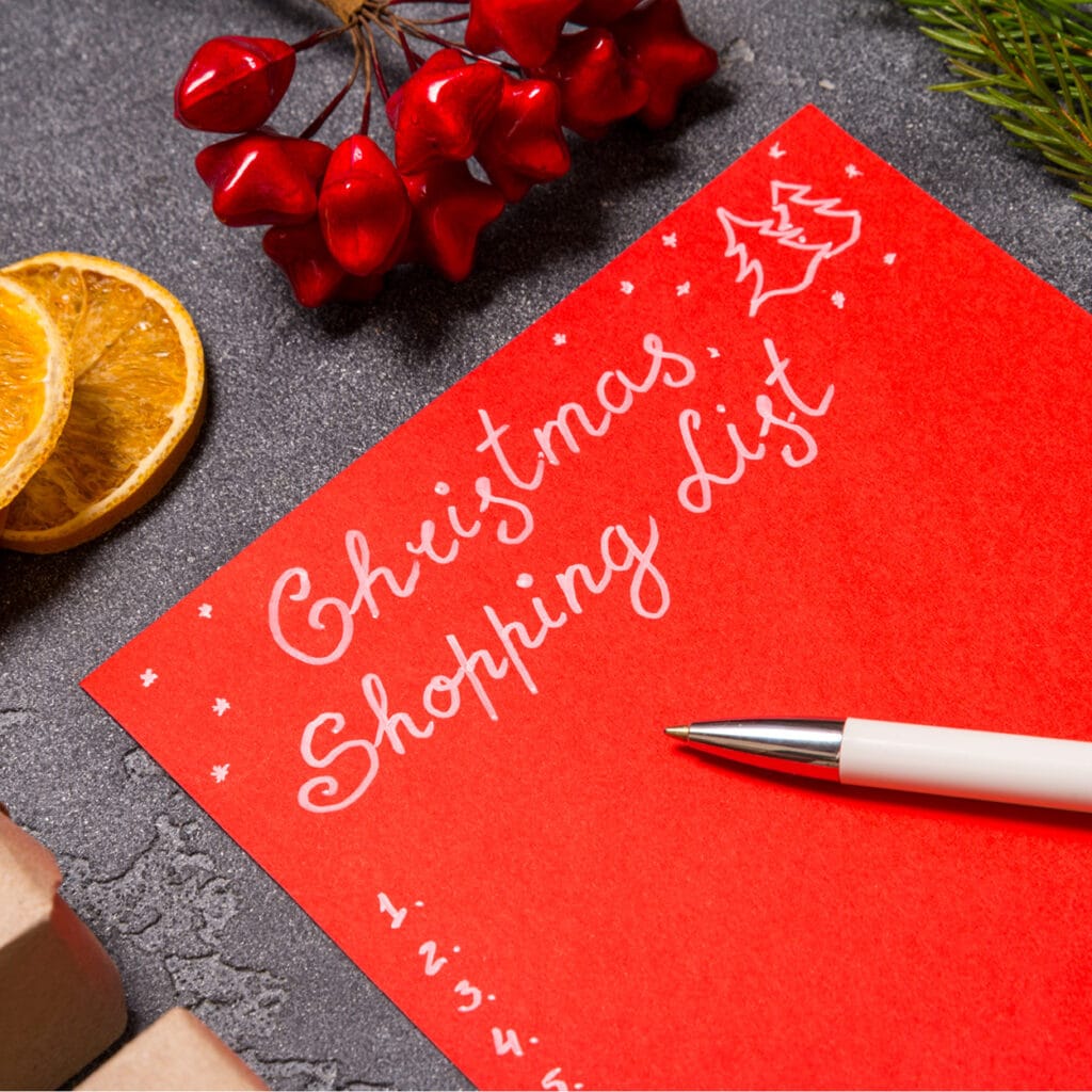 Rote Einkaufsliste mit Aufschrift „Christmas Shopping List“, dekoriert mit Trockenorange und roten Beeren