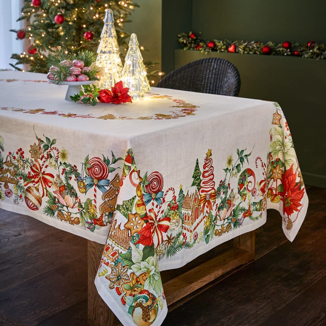 Weiße Tischdecke mit bunten Weihnachtsmotiven wie Zuckerstangen und Lebkuchenhaus