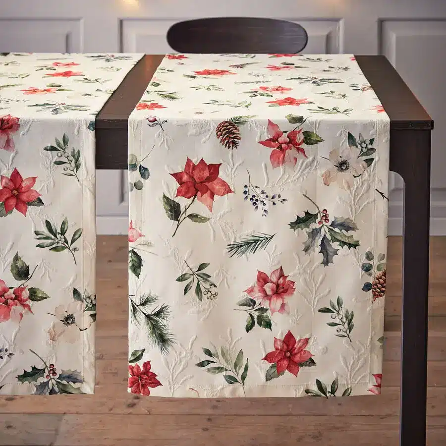Weihnachtlicher Matelassé-Tischläufer mit roten Sternblumen, Tannenzweigen und Wintermotiven