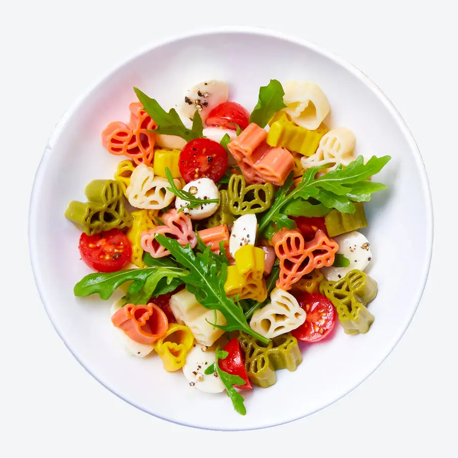 Bunte Osterpasta in Blumenform mit Kirschtomaten, Rucola und Mozzarella in wei&szlig;er Schale