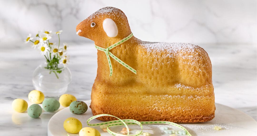 Klassisches Osterlamm aus Rührteig, mit Puderzucker bestäubt, auf heller Platte serviert